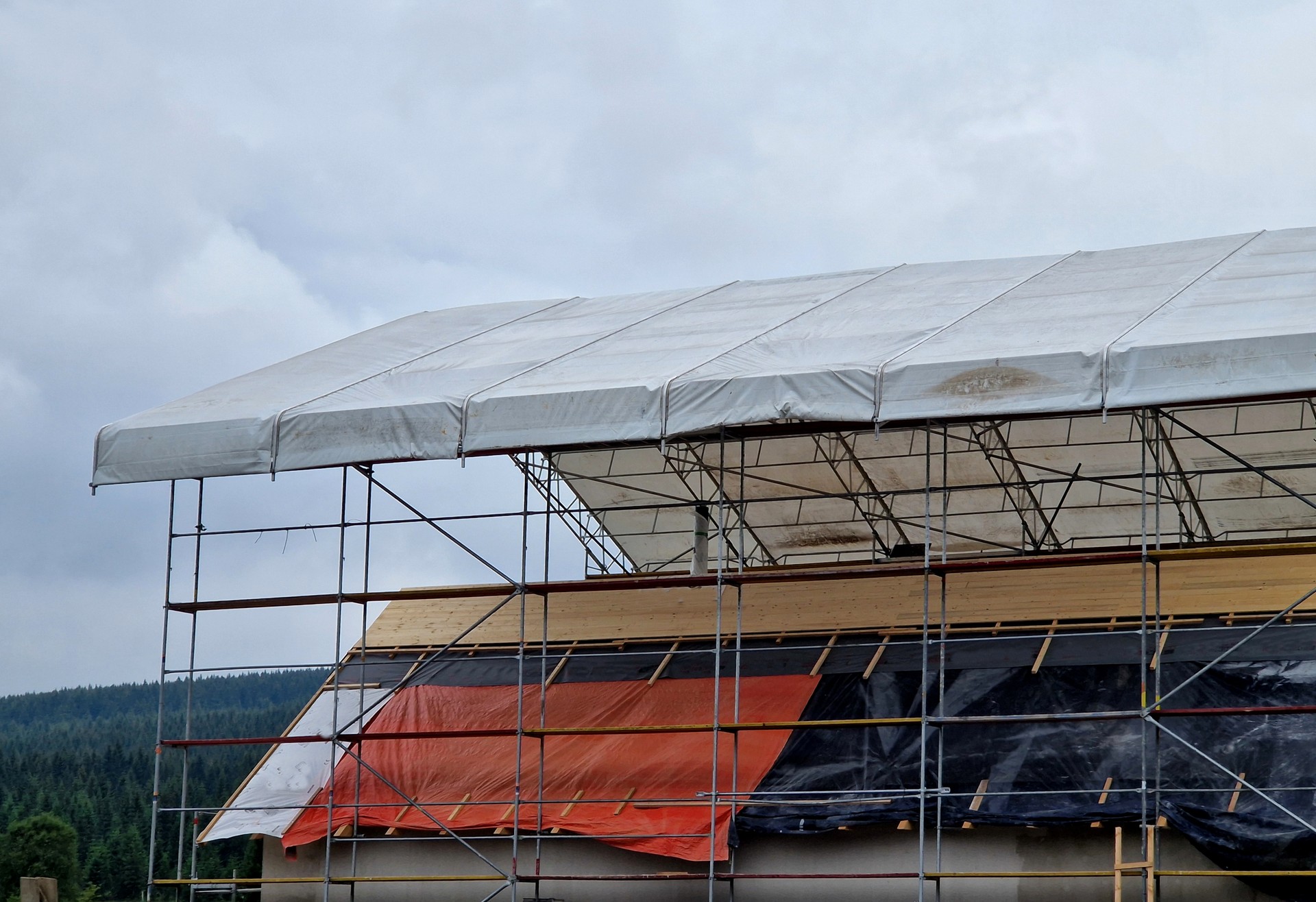 lattice, reconstruction of inhabited apartment building where entire floor is being demolished and tenants have not been evicted. additional roofing made of scaffolding and sails forms temporary roof